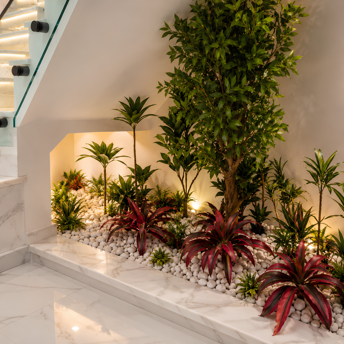 Création d’un jardin artificiel sous escalier avec galets blancs et éclairage intégré.