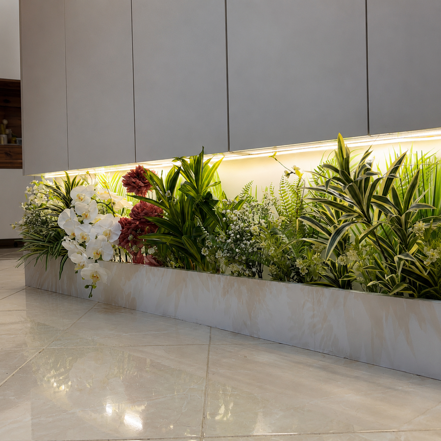 Jardin végétal artificiel composé d’orchidées blanches, de feuillages tropicaux et de fleurs décoratives dans une jardinière blanche, sous un éclairage LED chaleureux.