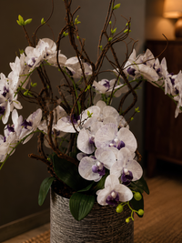 Gros plan sur les fleurs d’orchidées blanches et violettes artificielles réalistes, avec feuillage vert et pot décoratif, pour une décoration intérieure au Maroc