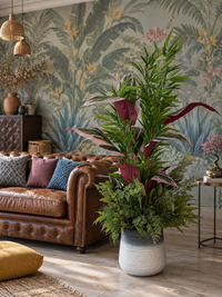 Arrangement tropical exclusif de 5 variétés de feuillage artificiel dans un salon au style tropical avec canapé en cuir marron