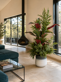 Arrangement tropical exclusif de 5 variétés de feuillage artificiel placé dans un grand salon moderne et lumineux
