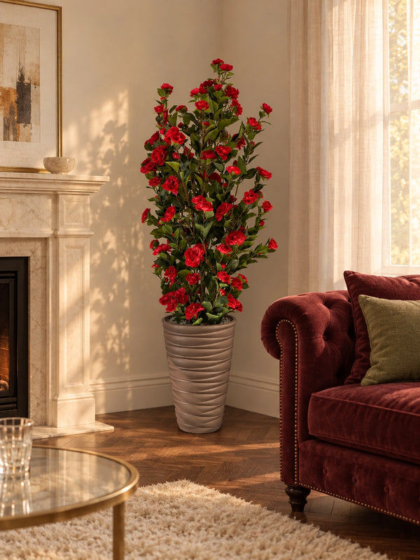 Grand Camélia artificiel 180 cm aux fleurs rouges éclatantes posé dans un salon élégant près d'une cheminée