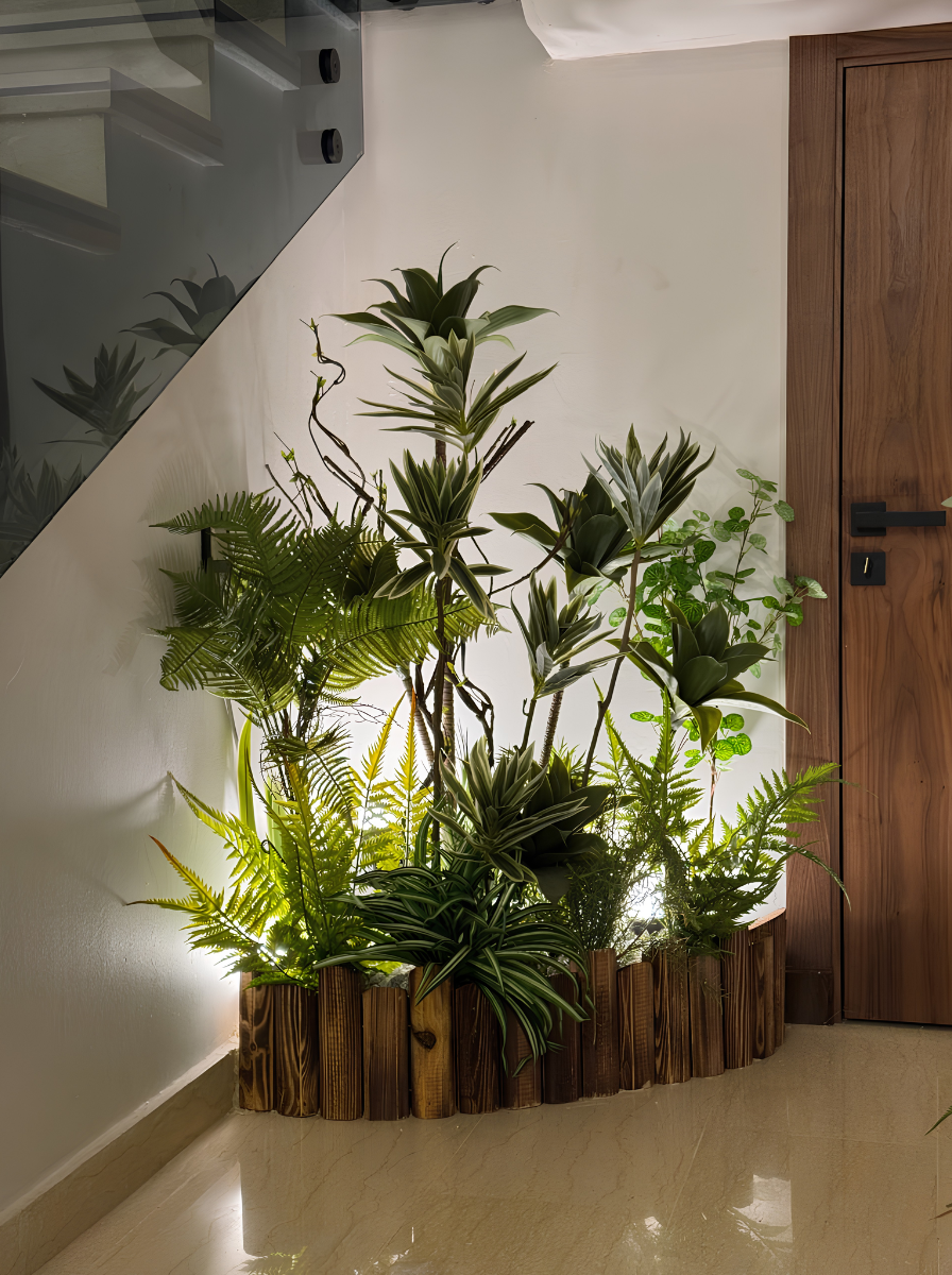 Aménagement d'un coin végétalisé sous un escalier avec des plantes artificielles et une bordure en bois pour décoration intérieure