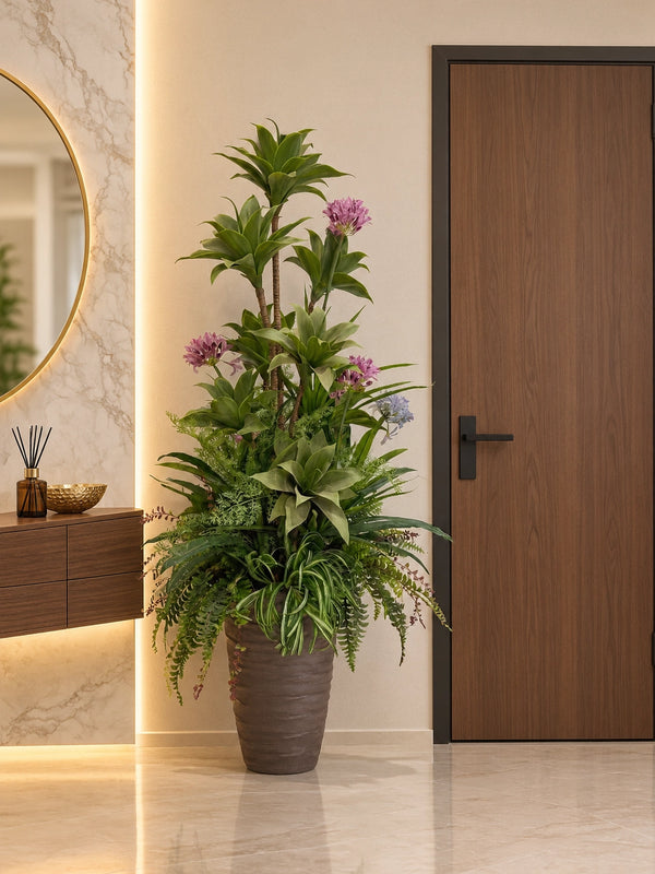 Grande composition florale artificielle avec agapanthes mauves et feuillages denses posée dans l'entrée d'une maison près d'une console et d'un miroir doré.