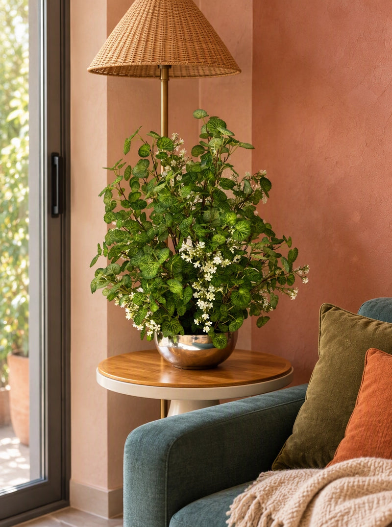 Fleur artificielle Begonia fleuri 70 cm posée sur une table basse en bois dans un salon moderne chaleureux avec canapé et lampe sur pied SaraFlora