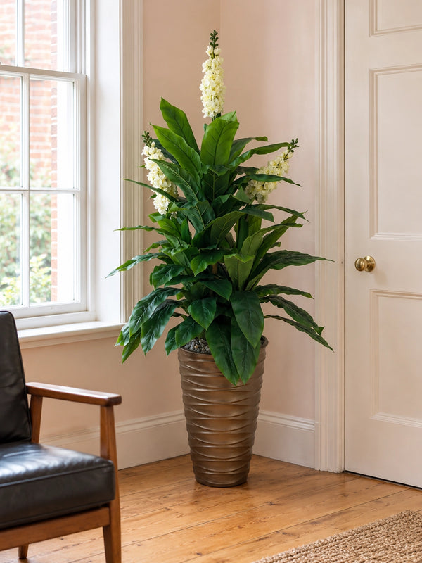 Plante artificielle Jacinthe blanche dans un pot bronze strié placée dans le coin d'un salon lumineux près d'une fenêtre et d'une porte