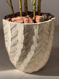 Gros plan sur le vase en porcelaine artisanale avec motifs géométriques en chevrons sculptés et finition en écorces de bois